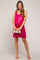 woman wearing a fuchsia sequined maternity dress highlighting her baby bump and holding a clutch purse