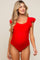 woman wearing a bright red maternity swimsuit with ruffle details on the shoulders and a visible baby bump