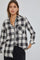woman wearing a black and white buffalo plaid button-down shirt with gold jewelry