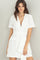 woman wearing a white short-sleeve belted shirt dress with pockets and a deep V-neckline