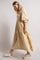 Woman wearing a yellow tiered midi dress with floral embroidery, smocked bodice, and puff sleeves with cream sneakers