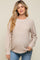 woman wearing a light beige knit maternity sweater and showing her baby bump
