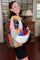 woman wearing a colorful patchwork maternity cardigan over a black maternity dress, showing her baby bump