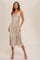 woman wearing a beige satin slip dress with lace trim and side slits, standing in a stylish pose