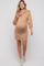 woman wearing a beige maternity sweater dress with a half zipper and balloon sleeves, showing her baby bump