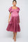 woman wearing a rose pink maternity dress with ruffled sleeves and a smocked bodice, highlighting her baby bump