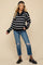 woman wearing a black and white striped maternity sweater with a half-zip and distressed jeans