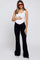 woman wearing a white maternity bodysuit and black flared maternity pants, holding her baby bump
