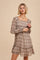 woman wearing a brown patterned long sleeve dress with a square neckline and tiered hem