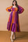 woman wearing a vibrant striped plus-size maxi dress with balloon sleeves and a tiered hem, paired with tan ankle boots