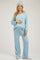 woman wearing a light blue maternity loungewear set with a v-neck top and wide-leg pants, holding her baby bump