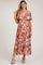 woman wearing a brown and pink floral maternity maxi dress with flutter sleeves and a deep v-neck, baby bump visible