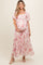 woman wearing a pink floral maternity maxi dress, holding her baby bump, with puff sleeves and a square neckline