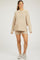 woman wearing a beige maternity oversized sweater and matching shorts with a visible baby bump