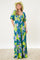 woman wearing a purple and green floral maxi dress with puff sleeves and a cinched waist, accessorized with a cowboy hat
