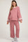 woman wearing a pink maternity loungewear set with white stripe details and wide sleeves, showcasing her baby bump
