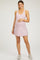 woman wearing a light pink maternity tank dress and holding her baby bump
