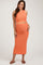 woman wearing a coral knit maternity two-piece set with a crop top and a fitted midi skirt, showing her baby bump