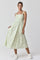 woman wearing a floral midi dress with adjustable straps and a smocked bodice, paired with white sneakers