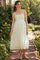 woman wearing a white floral maternity dress with spaghetti straps and a fitted bodice, standing in a garden pathway