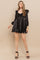 woman wearing a black satin mini dress with puff sleeves and a sweetheart neckline