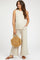 woman wearing a beige maternity sleeveless top and matching wide-leg pants, holding a woven handbag