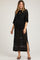woman wearing a black crochet maternity dress with a tie neck and side slits, showcasing her baby bump
