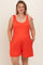 woman wearing a bright orange maternity plus romper with bow tie straps and pockets