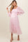 woman wearing a light pink maternity dress with puff sleeves and tiered skirt, showcasing her baby bump