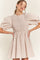 woman wearing a beige checkered mini dress with puff sleeves and smocked bodice