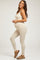 woman wearing a beige ribbed maternity jumpsuit showing her baby bump and paired with brown slip-on shoes