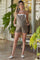 woman wearing a brown maternity romper with adjustable straps and pockets, showcasing her baby bump