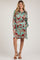 woman wearing a leafy print mint green maternity dress with a belted waist and long sleeves