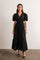 woman wearing a black puff sleeve maxi dress with a deep v-neck and tiered skirt