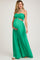 woman wearing a green strapless maternity jumpsuit with smocked bodice and flowing wide-leg pants, holding her baby bump
