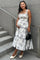 woman wearing a floral print maternity dress with a tiered skirt and holding her baby bump while standing on stairs
