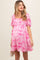 woman wearing a pink floral maternity dress with short puff sleeves and a fitted bodice, showing her baby bump