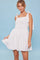 woman wearing a white sleeveless dress with tie straps and a flared skirt