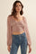 woman wearing a light pink cropped top with puff sleeves and ruched details, paired with blue jeans