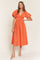 woman wearing an orange puff sleeve midi dress with a v-neck and gathered detailing