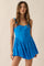 woman wearing a vibrant blue sleeveless mini dress with a fitted bodice and tiered skirt