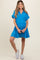 woman wearing a bright blue maternity dress with a collar and tiered skirt, showcasing her baby bump and paired with white sneakers