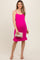 woman wearing a hot pink maternity dress with ruffle hem and spaghetti straps, holding a clutch and showing her baby bump