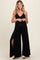 woman wearing a black maternity jumpsuit with a tie waist and side slits, showcasing her baby bump