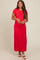 woman wearing a bright red short sleeve maternity maxi dress and cradling her baby bump