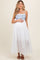 woman wearing a white maxi maternity dress with blue embroidered details and holding her baby bump