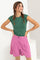 woman wearing a green cap sleeve top paired with pink high-waisted shorts