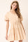 woman wearing a peach puff sleeve tiered dress with buttons and an elastic waist