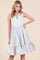 woman wearing a white and navy striped sleeveless tiered dress with a v-neckline