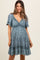 woman wearing a blue floral print maternity dress with short sleeves and a gathered waist, showcasing a baby bump
